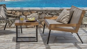 Une terrasse avec une table et deux chaises, d’où l’on peut admirer une vue sur la côte, avec un bateau visible au loin.
