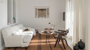 A modern living room with a white sofa, a small round table, and a wooden chair.