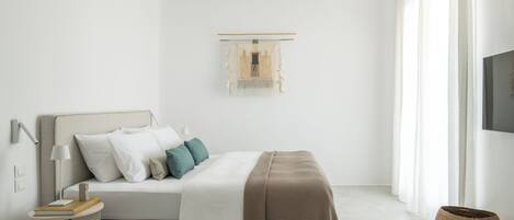A minimalist bedroom with a bed, bedside table, lamp, and a mounted TV.