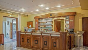 A bar area with wooden cabinets, shelves with glasses, and a marble pedestal. - Regia Panzió és Étterem (Halászi)