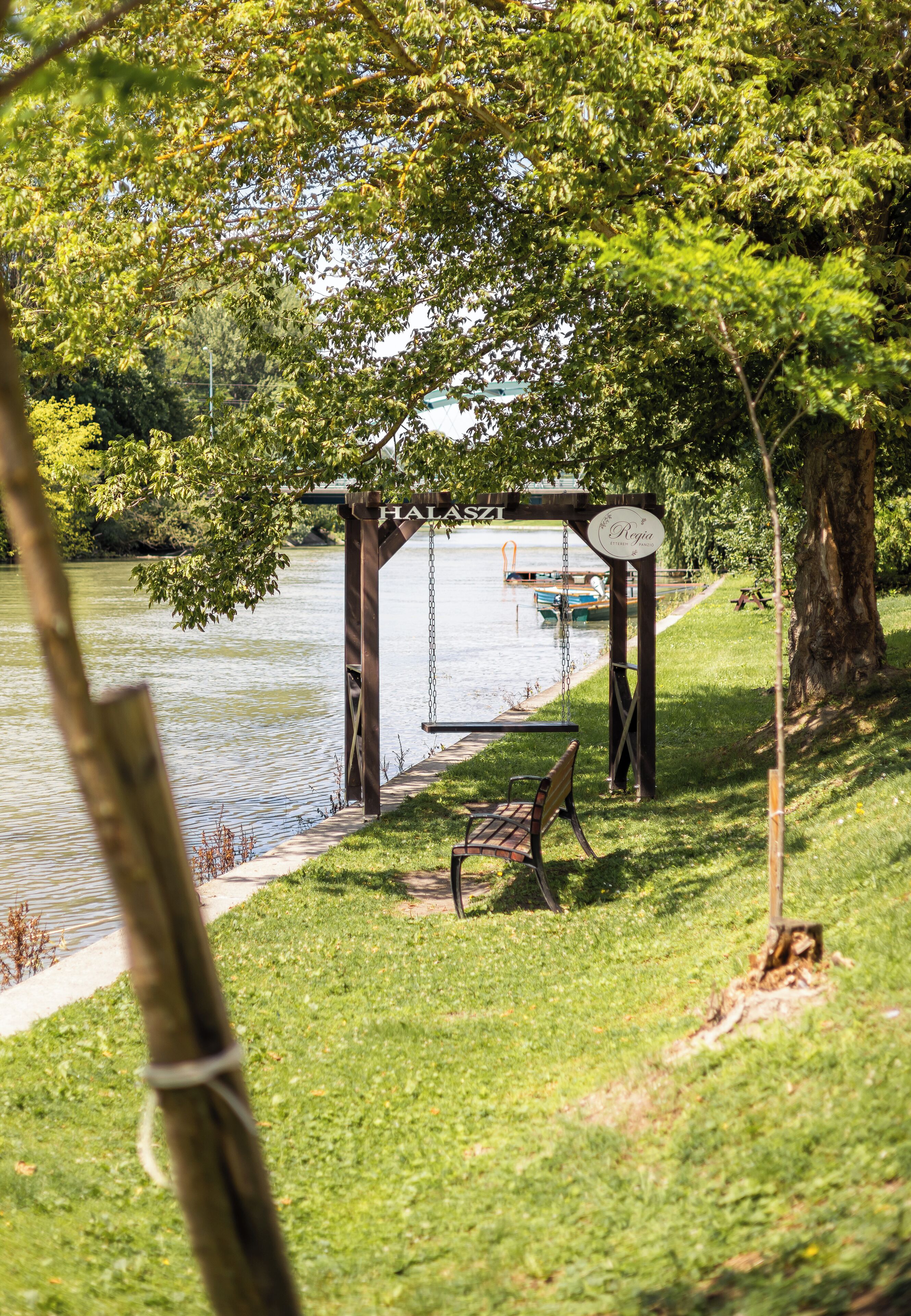 A gazebo by a lake with a bench and a swing.