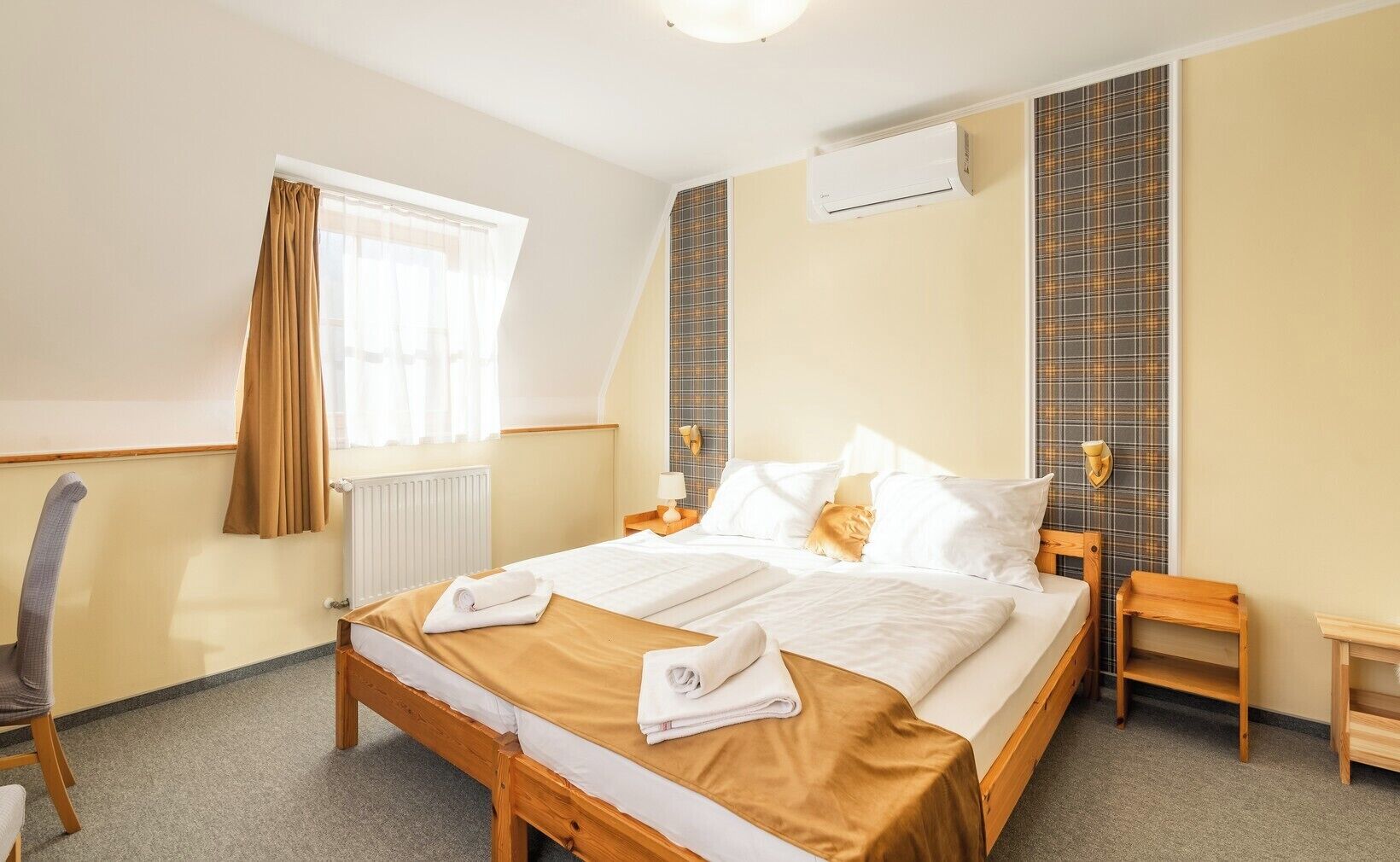 Una habitación de hotel con una cama grande, una silla de madera, una mesita de noche y una ventana con cortinas.