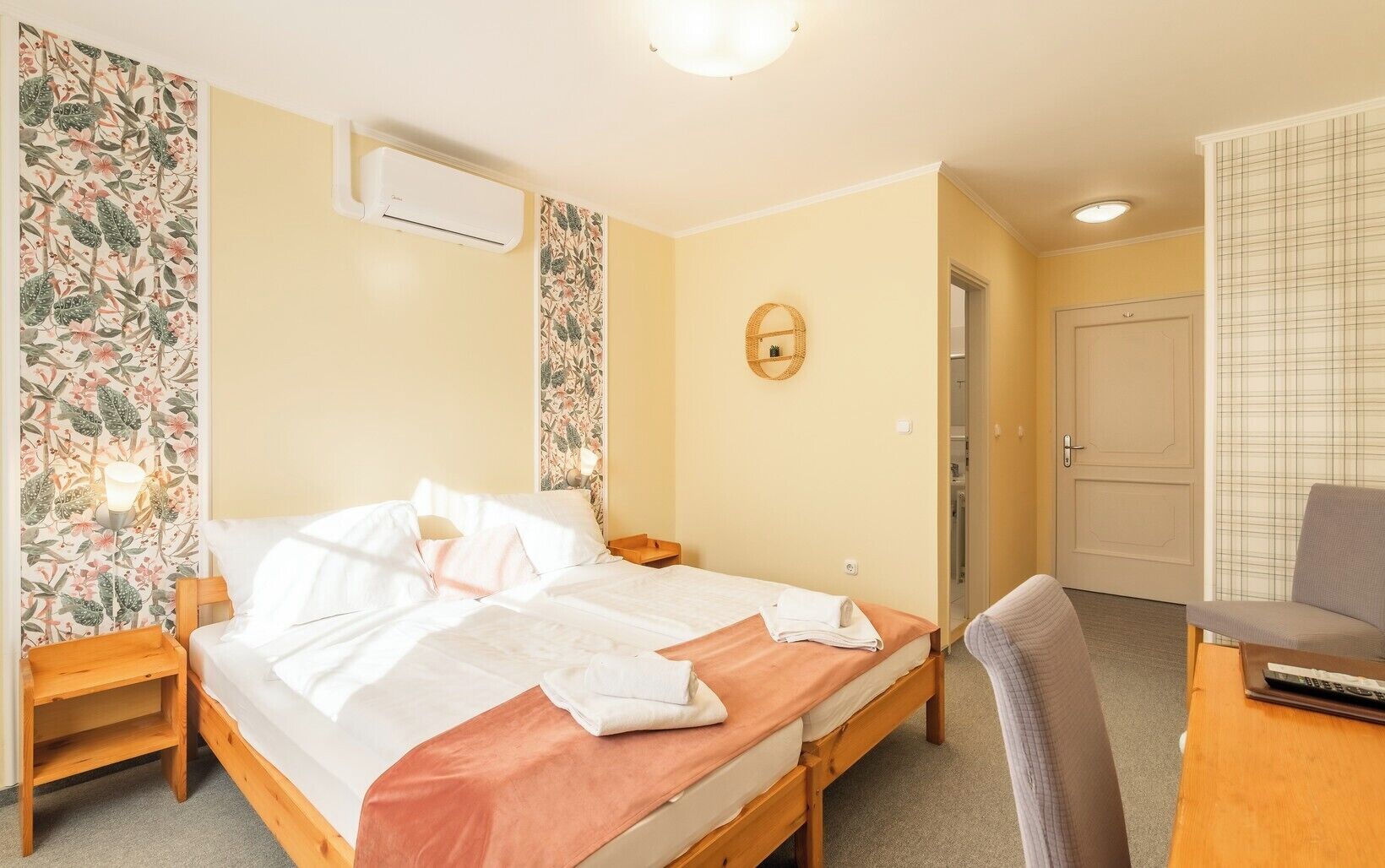 Une chambre d’hôtel équipée d’un lit double, d’une table de chevet, d’une chaise, d’un bureau et d’un appareil de climatisation.