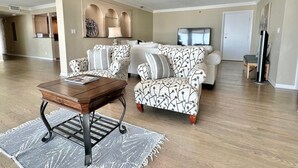 A spacious living room with a wooden coffee table, patterned armchairs, and a sofa.