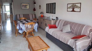 Ein gemütliches Wohnzimmer mit einer gestreiften Couch, einem Holzespeisetisch mit Stühlen und einer Küche im Hintergrund.