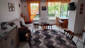 Ein gemütliches Zimmer mit einem Bett, einem Esstisch mit Stühlen, einem kleinen runden Tisch und einem an der Wand befestigten Fernseher.