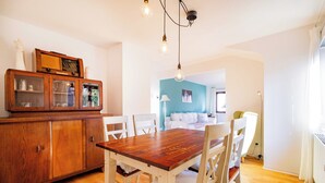 Un comedor con una mesa y sillas de madera, un armario con puertas de cristal y una lámpara en el techo.