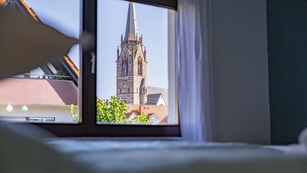 Vista por la ventana de una torre de iglesia bajo un cielo despejado.