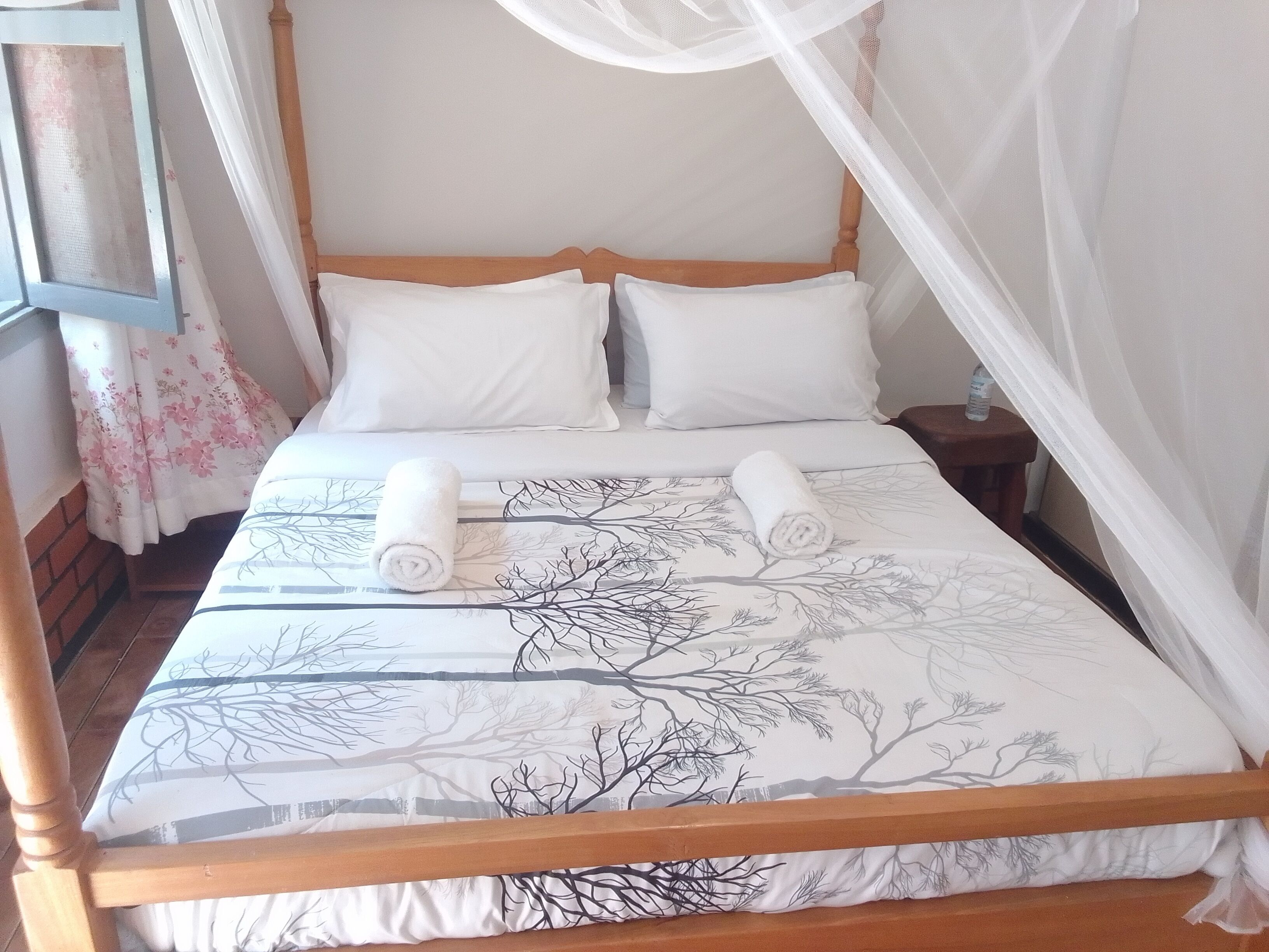 A bed with a canopy, two pillows, and two rolled towels.