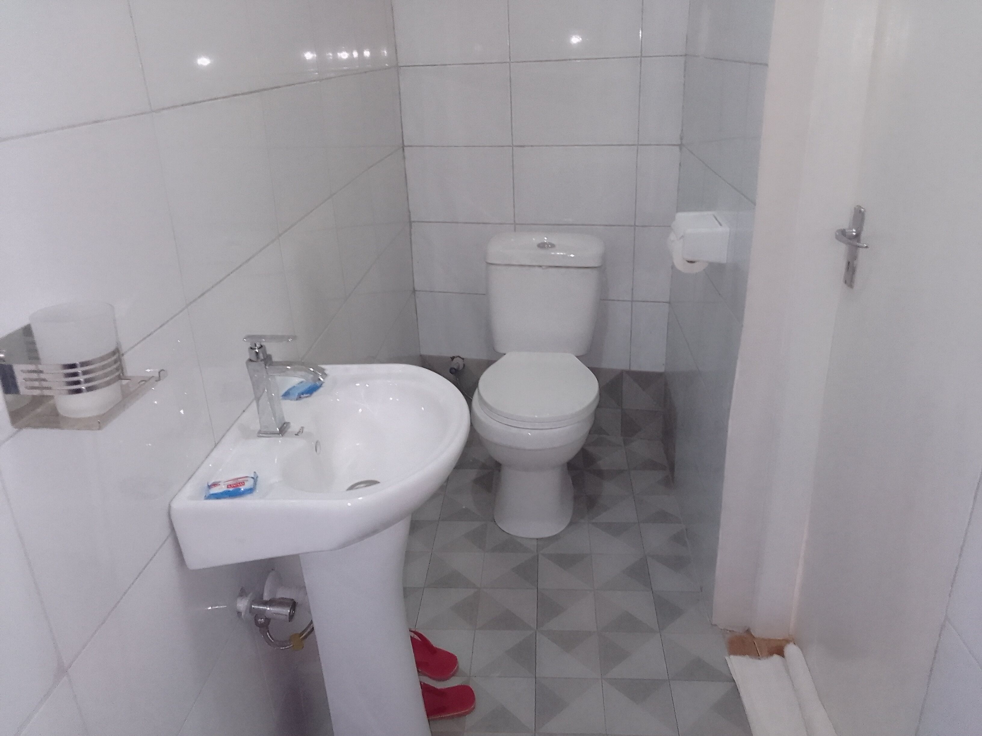 A small bathroom with a white sink, toilet, and a toilet paper holder.