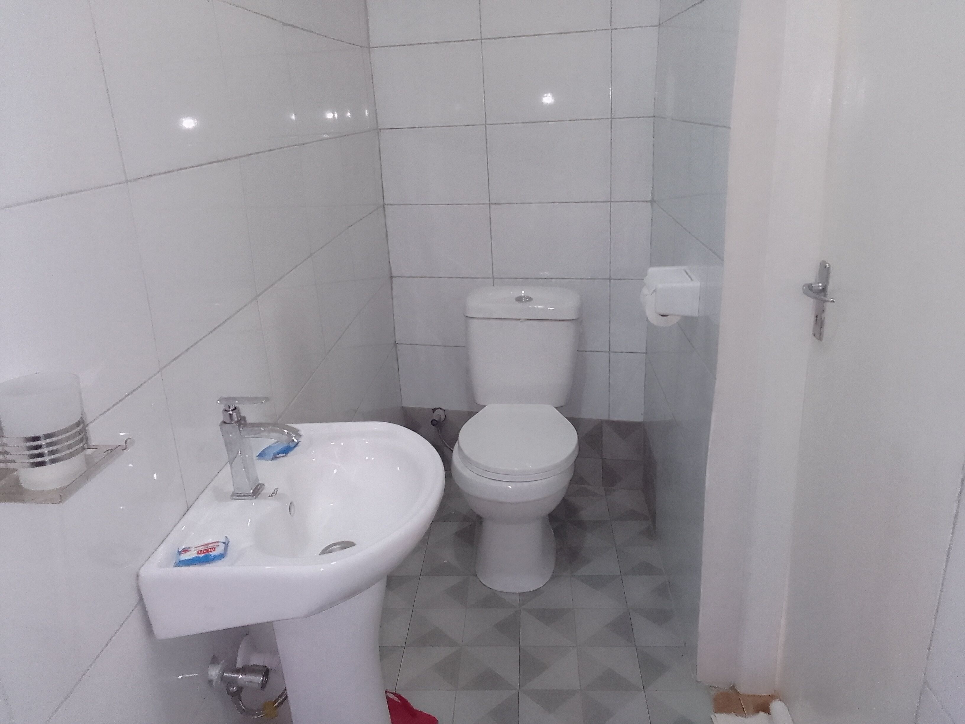 Un baño pequeño con lavamanos blanco, inodoro y suelo de baldosas.