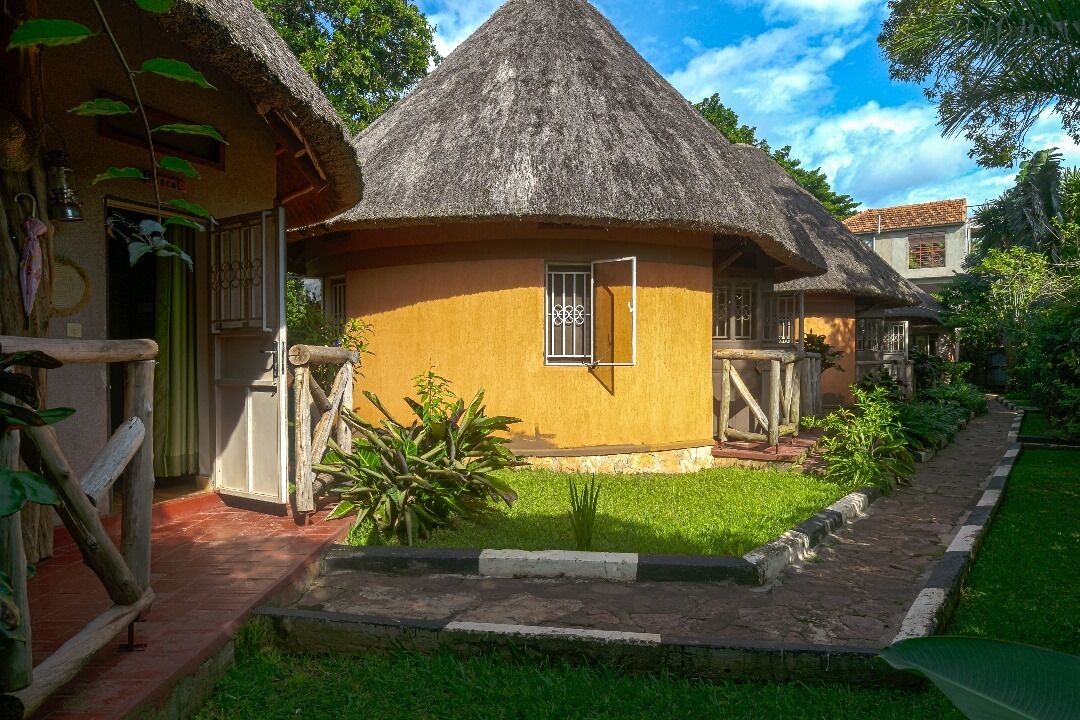 Een rieten huis met een klein raam, omringd door een verzorgde tuin.