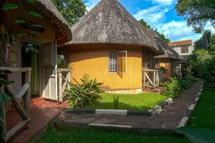 Una casa con techo de paja y una ventana pequeña, rodeada por un jardín cuidado.