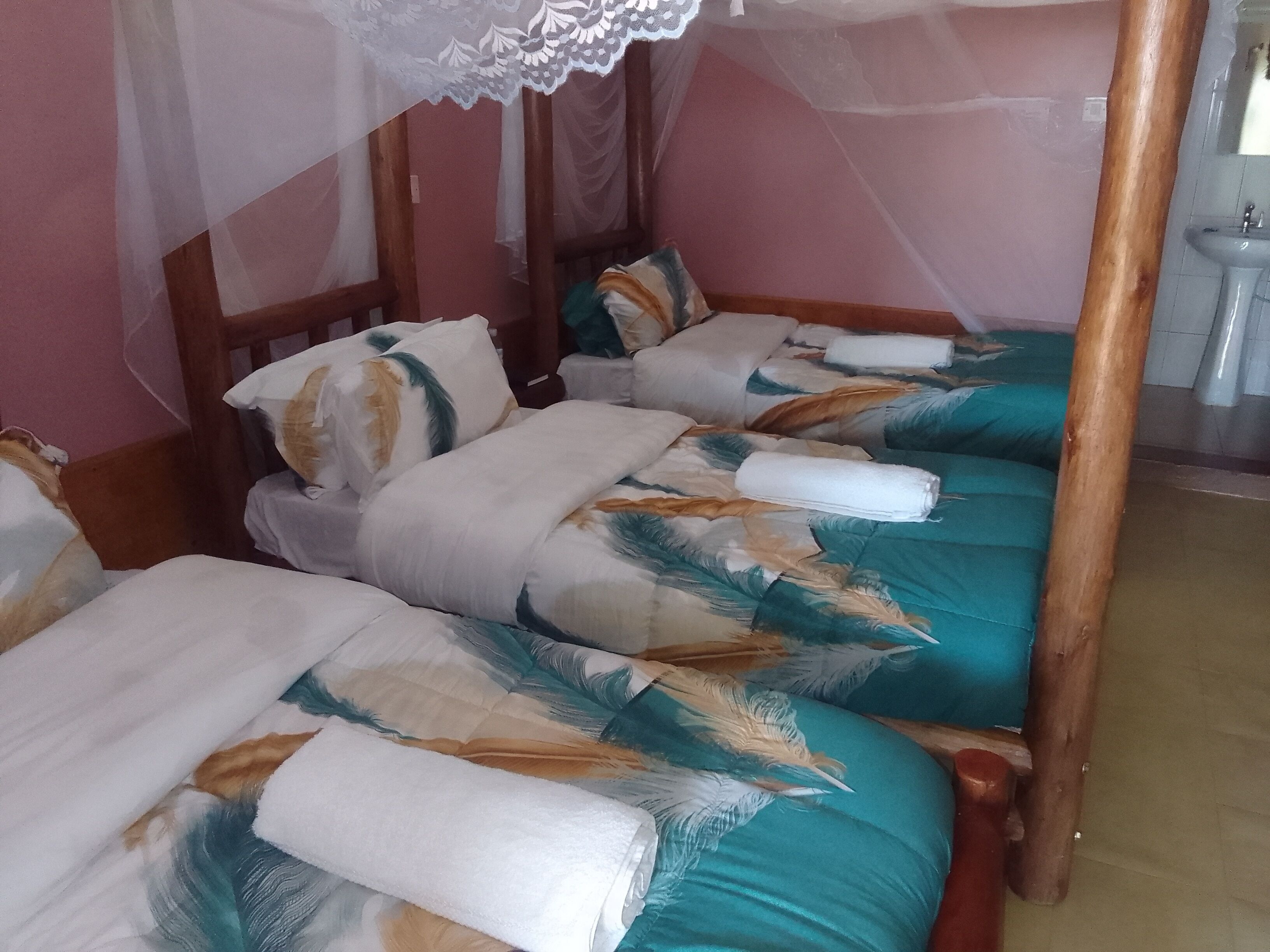 Une chambre avec quatre lits simples, chacun doté d’un baldaquin et d’oreillers.