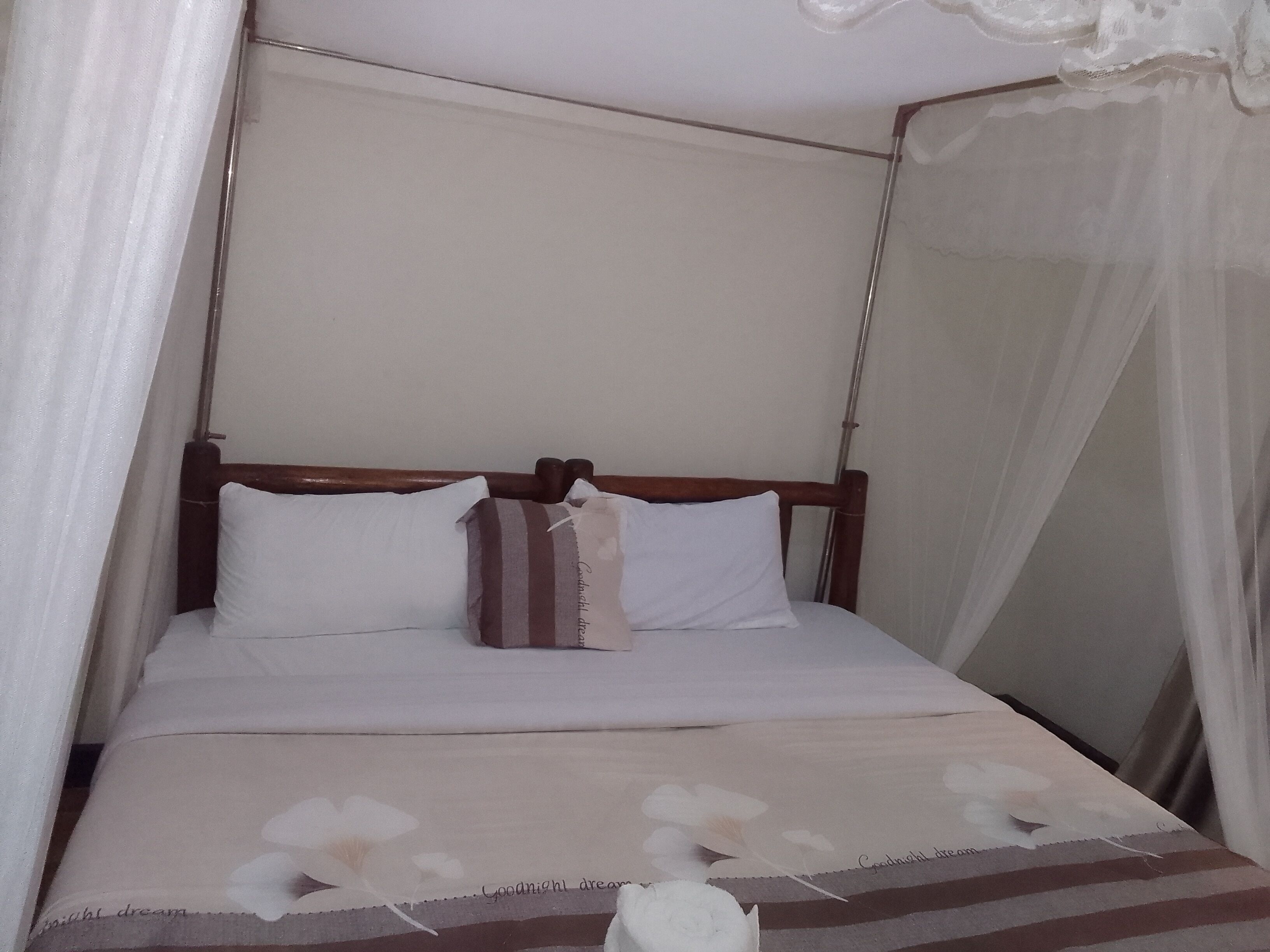 A bed with a wooden headboard, white bedding, and a floral-patterned blanket.