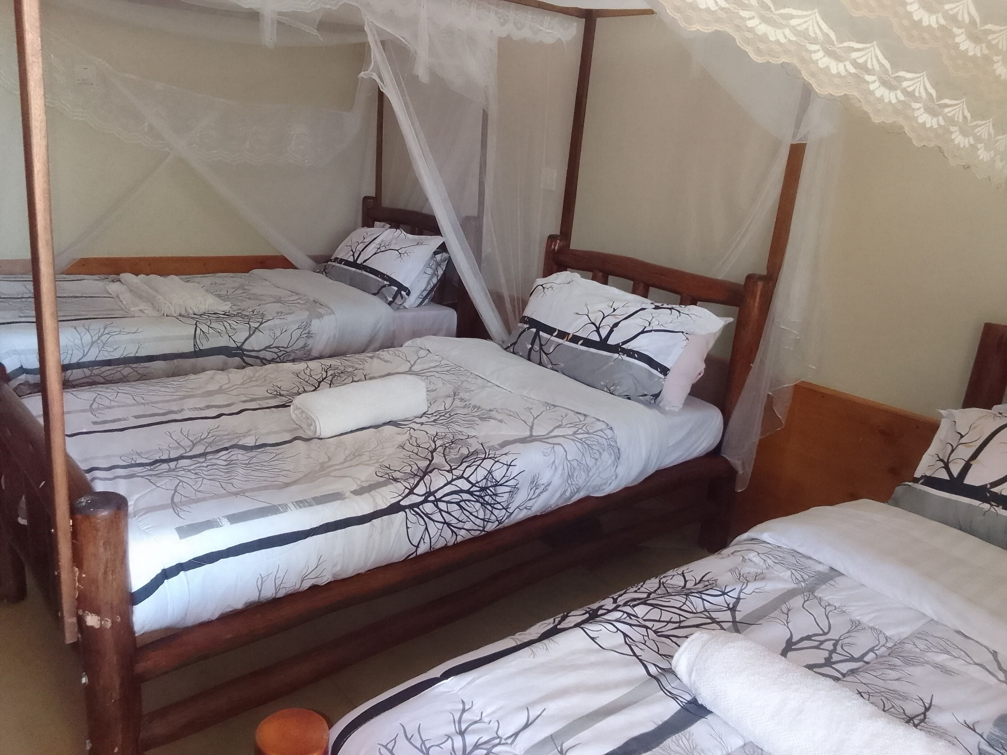 Una habitación con dos camas de madera, cada una con dosel y cubrepierna con estampado de árbol.