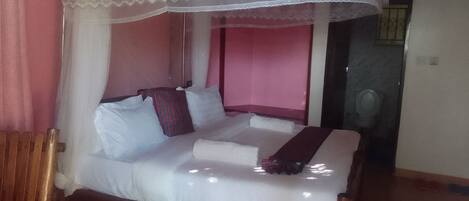 A bed with a canopy, a wooden headboard, and a red wall.