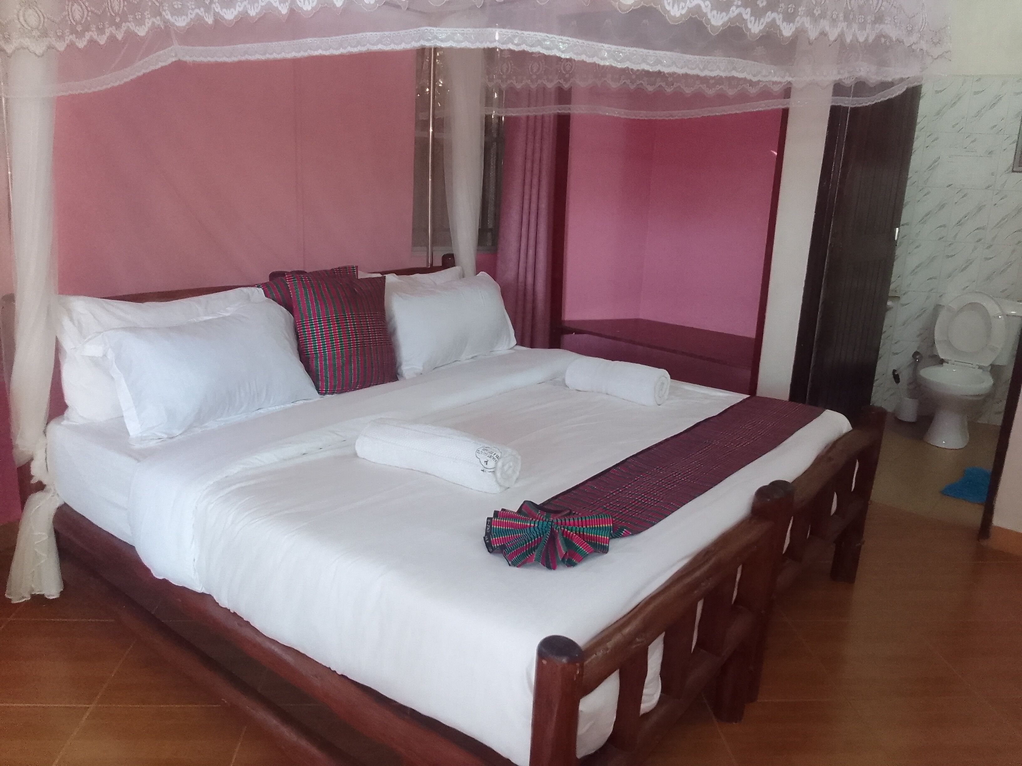 Een bed met witte lakens, een houten hoofdbord en een hemelbed.