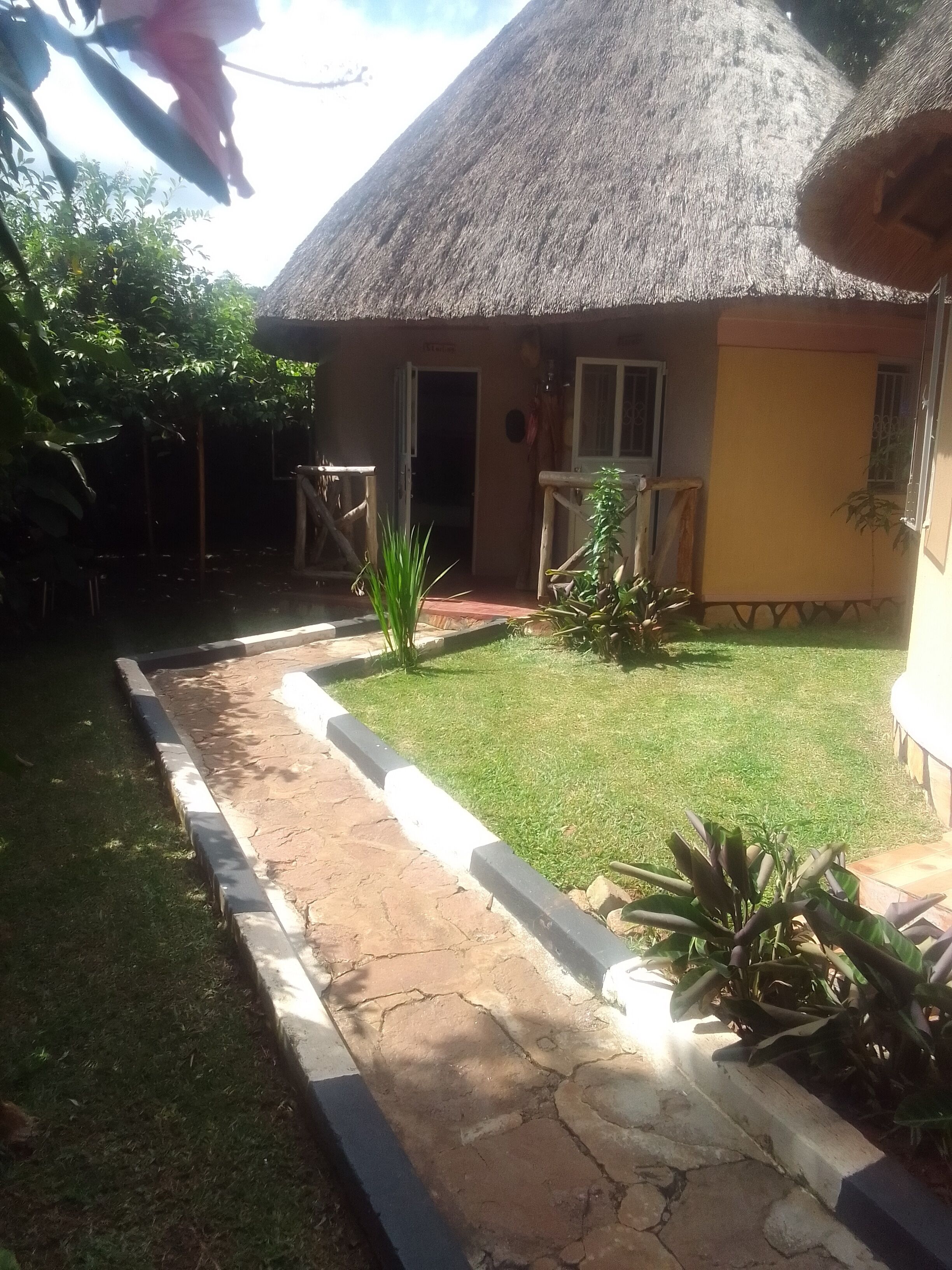 A house with a thatched roof, a paved entrance, and a well-maintained lawn.