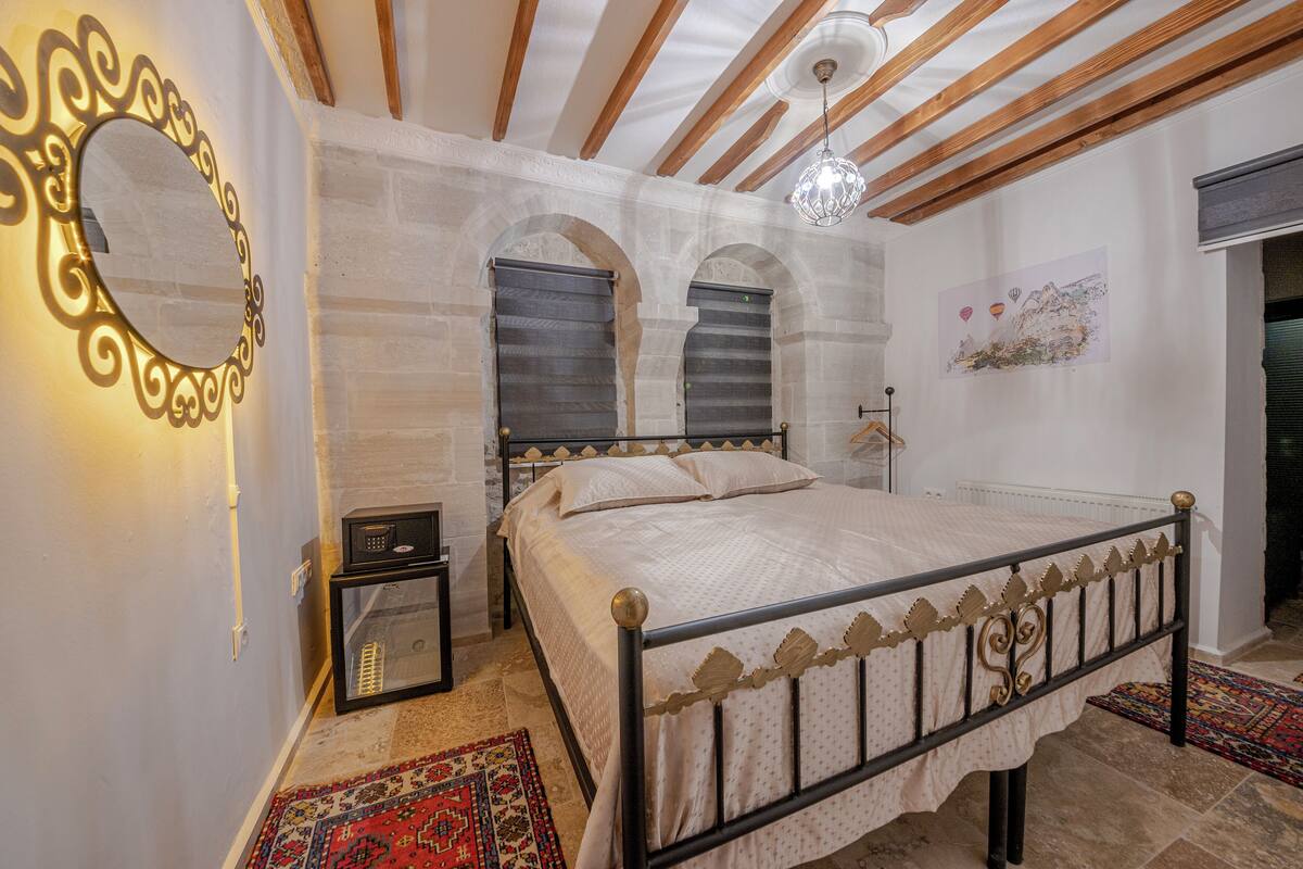 A bedroom with a bed, a nightstand, a mirror, and a radiator.