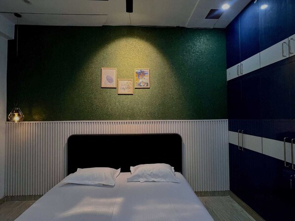 A bedroom with a bed, a radiator, a wall with artwork, and a wardrobe. - GET DREAM INN (Noida)