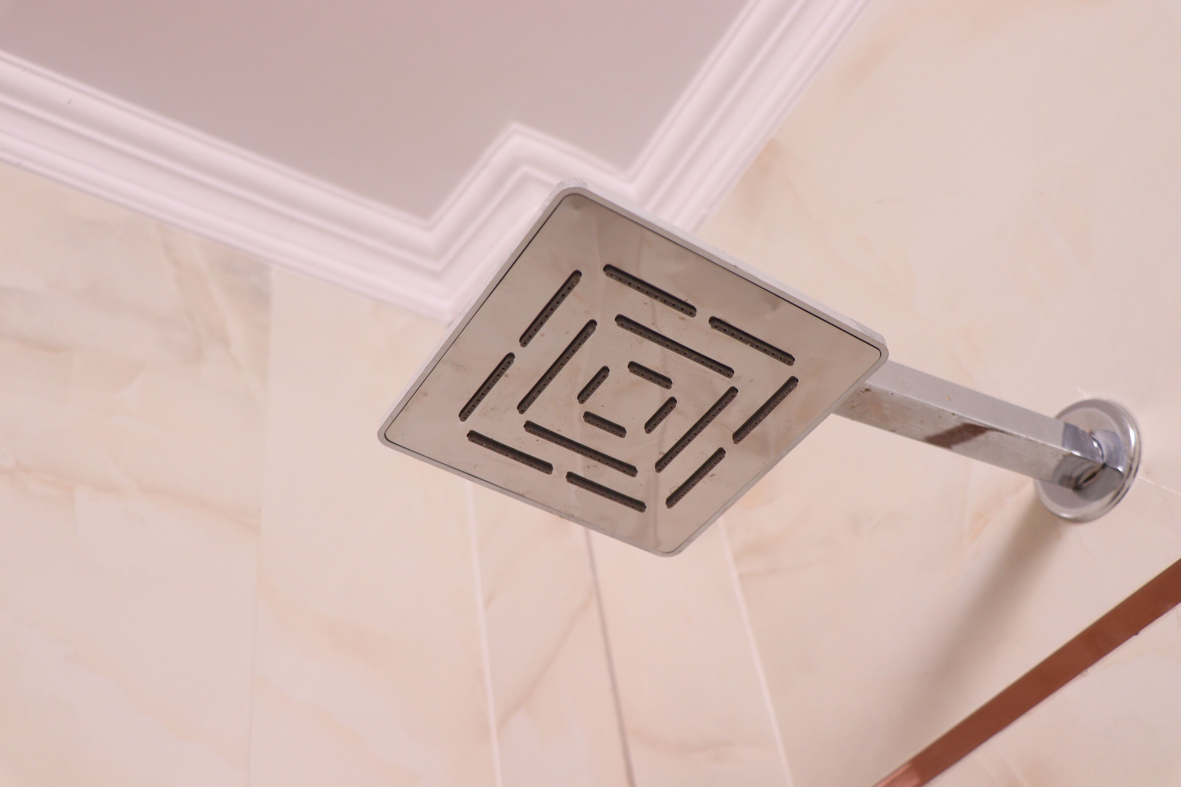 A bathroom with a modern shower head mounted on a wall.
