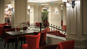 A dining area with a long table and red upholstered chairs, white walls, and chandeliers. - Alpin Aparthotel 2302 (Brasov)