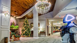 A lobby with a large Christmas tree, a robot, and a chandelier. - Alpin Aparthotel 2302 (Brasov)