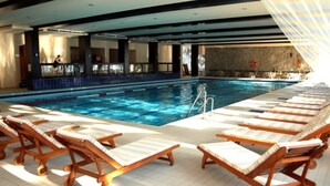 A swimming pool with lounge chairs and a bar area. - Alpin Aparthotel 2302 (Brasov)