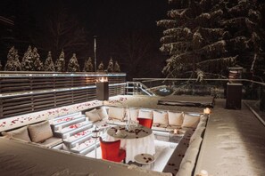 An outdoor seating area with tables and chairs, surrounded by snow-covered trees and a railing. - Alpin Aparthotel 2302 (Brasov)