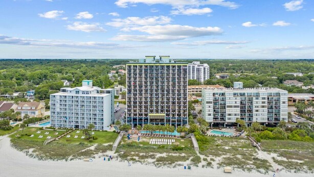 Et højt hotel med flere etager, en swimmingpool og en badestrand.