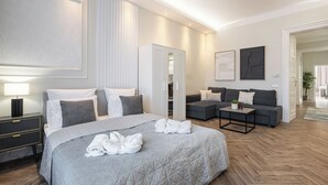 A modern hotel room with a large bed, a sofa, and a small table. - The Prestige L’Or Suite 4-BDR with two balcony (Budapest)