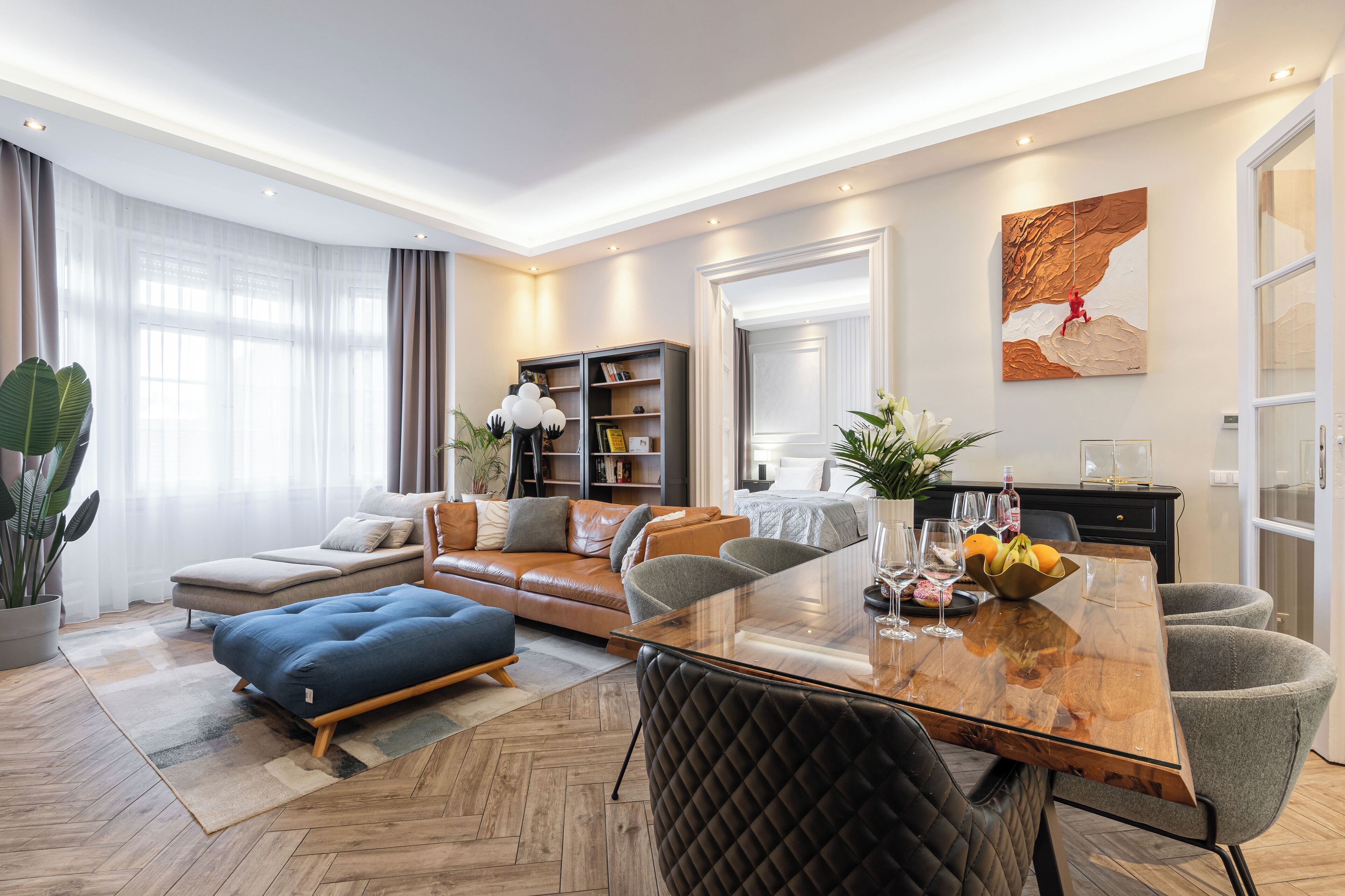 A modern living room with a sofa, ottoman, and a glass-top dining table.