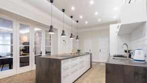 A modern kitchen with a large island, pendant lighting, and a herringbone wood floor. - The Prestige L’Or Suite 4-BDR with two balcony (Budapest)