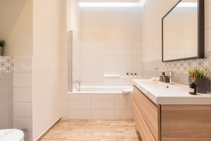 A modern bathroom with a bathtub, a sink, and a mirror. - The Prestige L’Or Suite 4-BDR with two balcony (Budapest)