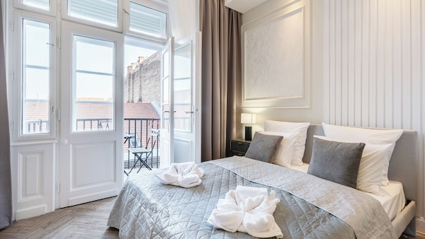A hotel room with a large bed, a balcony, and a view of the city. - The Prestige L’Or Suite 4-BDR with two balcony (Budapest)