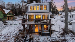 A two-story house with a balcony and a hot tub on the ground floor. - Lakefront, Mtn Views, Hot Tub, Game Room, & More! (Gilford)