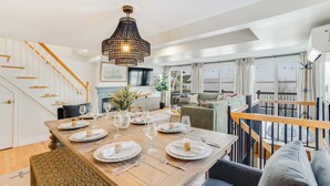A dining area with a wooden table set for six, a staircase, and a view of the outdoors. - Lakefront, Mtn Views, Hot Tub, Game Room, & More! (Gilford)