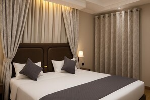 Une chambre d’hôtel avec un grand lit, deux oreillers, une tête de lit et des rideaux.