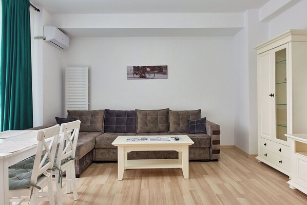 Uma sala de estar com sofá, mesa de centro, armário e radiador.