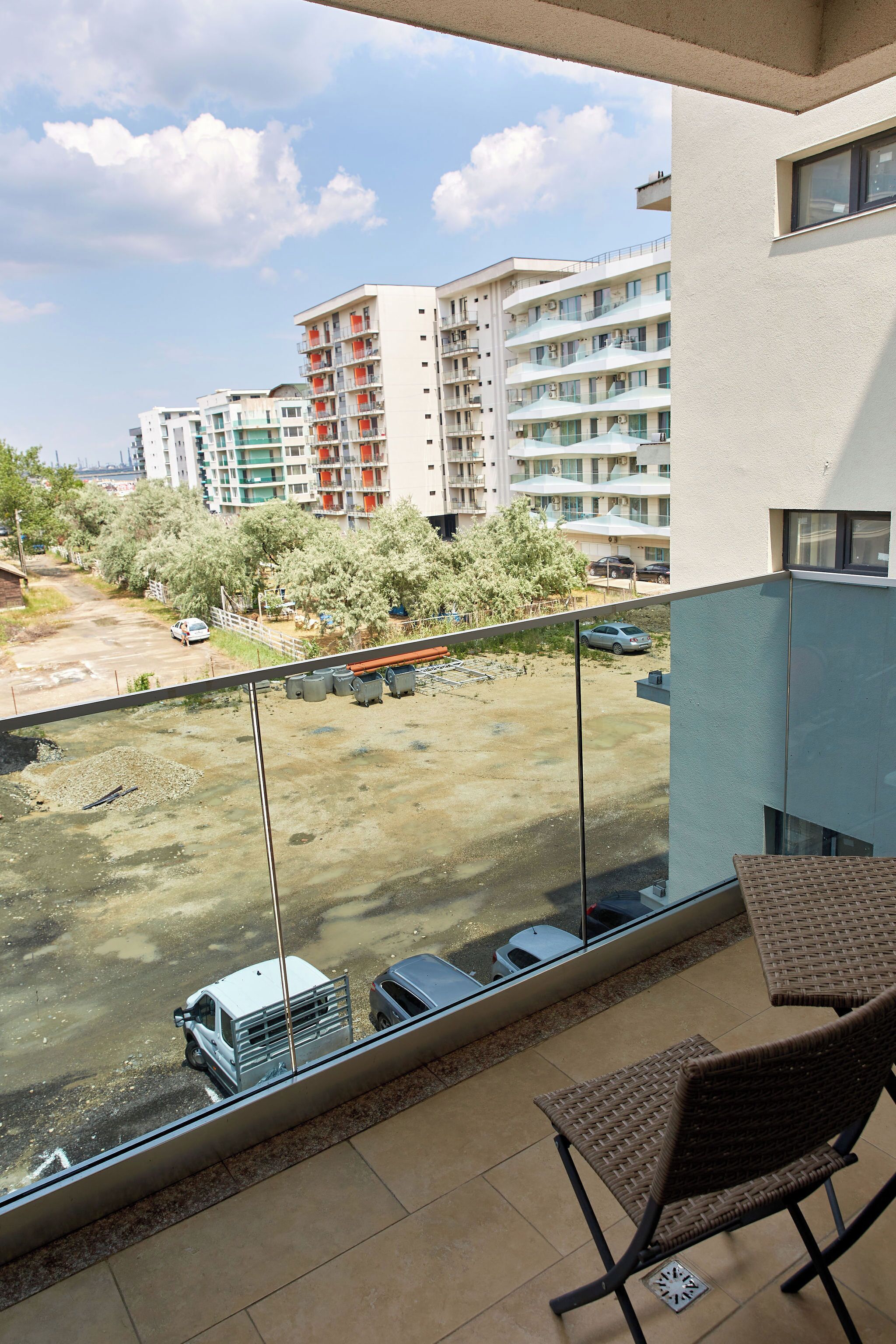 A balcony with a view of a parking area and a building with multiple floors and balconies.