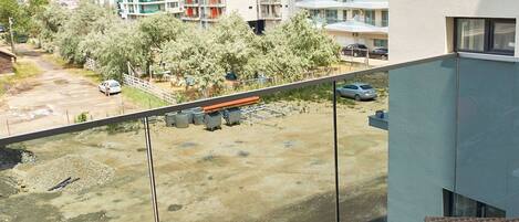 A balcony with a view of a parking area and a building with multiple floors and balconies.