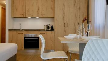 A modern kitchen with wooden cabinets, a dining area with white chairs, and a small table set for two.