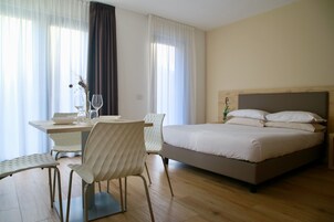 A hotel room with a bed, a dining table with chairs, and a window with curtains.