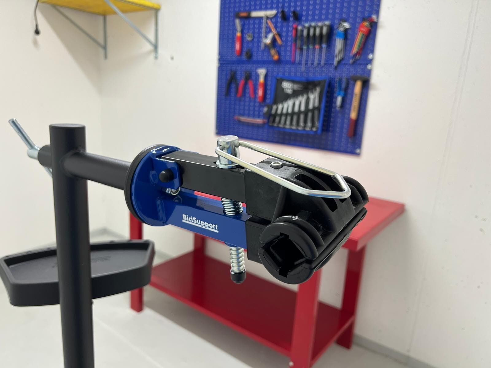 Un soporte para reparación de bicicletas BiciSupport azul con abrazadera de manillar negra y una base roja y negra.
