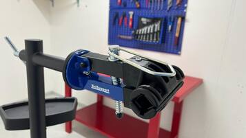 Un cavalletto per riparare biciclette BiciSupport blu, dotato di morsetto nero per manubrio e base rossa e nera.