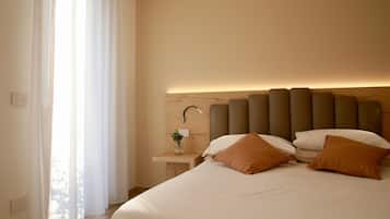 Un dormitorio moderno con una cama grande, una mesita de noche con un florero y un cabecero con iluminación integrada.