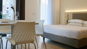 A modern hotel room with a bed, a dining table with chairs, and a large window with curtains. - Bernina Suites - 150 metres to Bernina Express (Tirano)