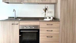 A modern kitchen with wooden cabinets, a stainless steel sink, and a built-in oven. - Bernina Suites - 150 metres to Bernina Express (Tirano)