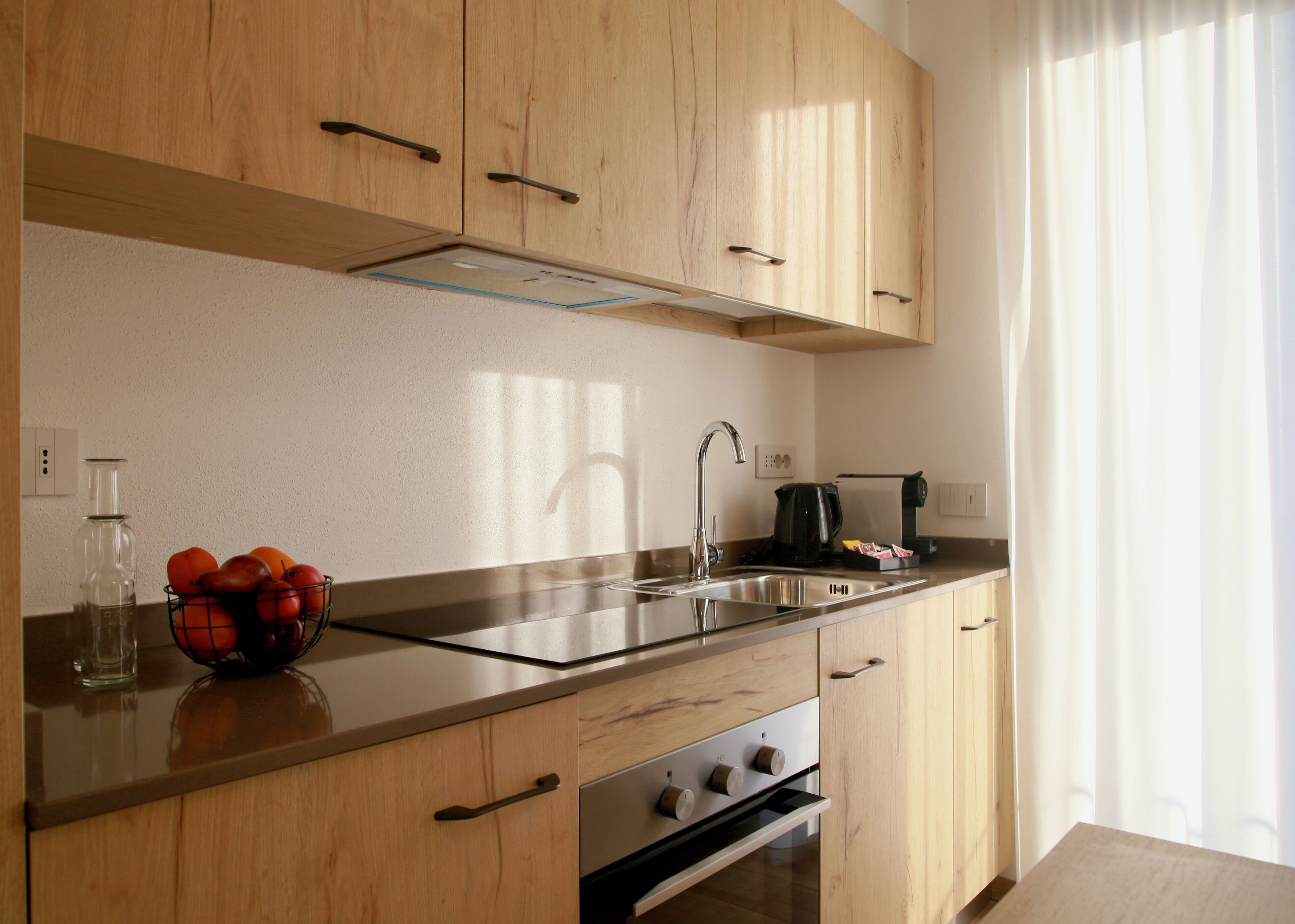 A modern kitchen with wooden cabinets, a stainless steel sink, and a built-in oven.